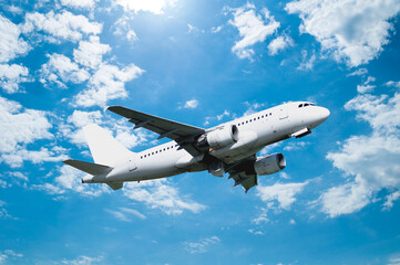 Airplane with blank livery flying in the blue cloudy sky - travel background with commercial airplane in the flight