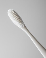 A close-up of a white toothbrush with soft bristles against a plain white background.