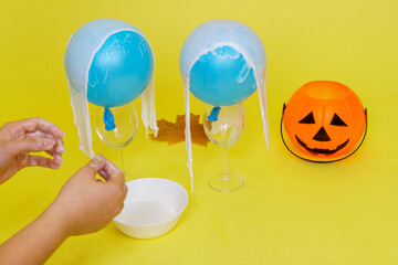 DIY Halloween ghost craft made from bandages and glue. We put bandages in glue on the balls. Step 3.