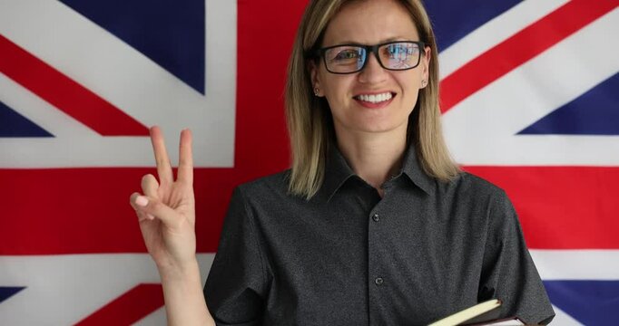 Portrait of confident smiling immigrant female student holding notepads in hands and making gesture of approval. Confidence sign over UK flag