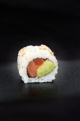 close up sushi roll . maki avocado salmon isolated on black background 