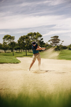 Male golfer executing a sand shot with perfect follow through during a round of 18 holes