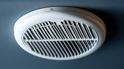 Close-up view of a round ceiling ventilation grille with vertical slats and metallic finish installed in a room.