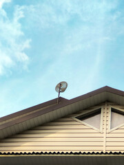 antenna for internet and television, satellite dish on the roof of the house attic attic window roof tiles sky clouds. satellite technology placement