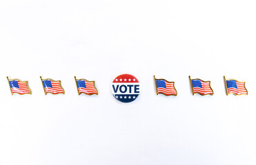 Vote button with American flag pins in horizontal arrangement placed in the center with six American flag pins symmetrically aligned in a horizontal row on a white background. importance of civic duty