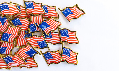 Collection of American flag pins on white background. Small American flag pins scattered on a white surface. The pins feature the iconic red, white, and blue design with gold edges,patriotism 
