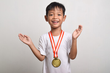 Asian boy with a gold medal isolated on a white background with a surprised facial expression....