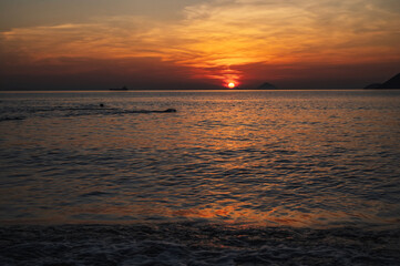 Silhouettes of people swimming in the sea at sunrise in the morning on vacation at a resort in summer