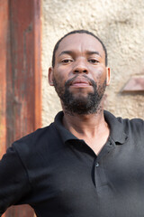 african village, portrait of african man with a beard in front of the house