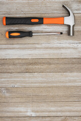 Retro orange screwdriver and hammer on wood background