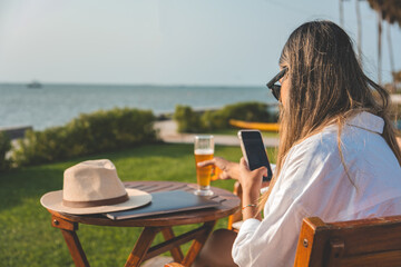 A woman is sitting at a table by the ocean, remote work concept