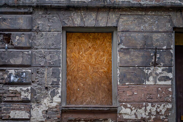 an old, dilapidated tenement house that has not been renovated for a long time with a boarded-up window and a wooden entrance. abandoned building in the city center.