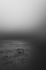 A dark black and white space with an empty floor, foggy in a cinematic and minimalist style