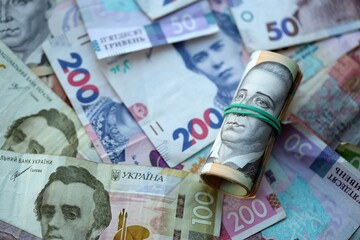 Roll of 500 Ukrainian Hryvnia money bills lies on big pile of ukrainian currency money close up