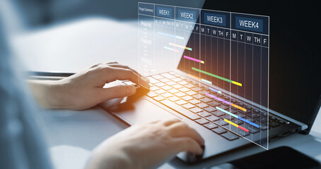 Project manager working on laptop and updating tasks and milestones progress planning with Gantt chart scheduling interface for company on virtual screen. Business Data Management System.	