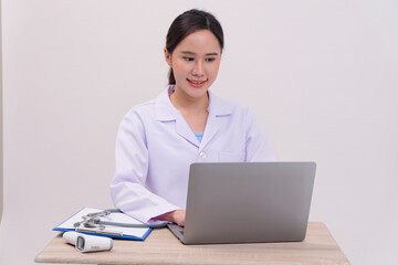 Asian female doctor sitting and working with laptop, white background.