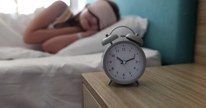 Alarm clock for 10 o'clock on table in children bedroom. Child teenager sleeping in sleep mask