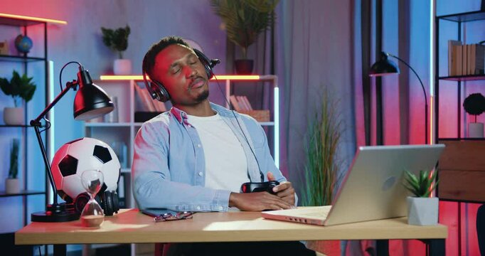 Active man in headset is dissatisfied when lost the opportunity to win video game on laptop at home in the evening. Leisure concept