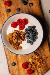 A bowl of yogurt parfait with granola, raspberries, and blueberries.