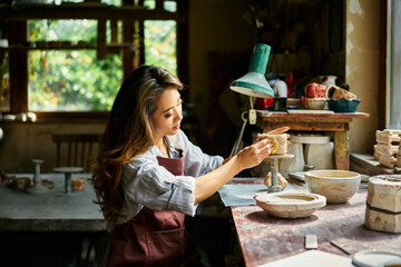 Female artist sculpts crafts with ceramic clay at her creative workshop