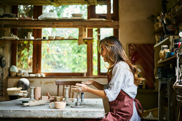 Female artist sculpts crafts with ceramic clay at her creative workshop