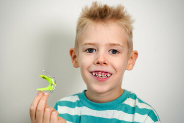 A blond-haired boy inserts orthodontic plate into his mouth to expand jaw and teeth. Close-up....