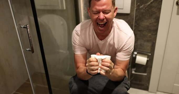 Man with problem sitting on toilet closeup. Constipation diarrhea and abdominal pain