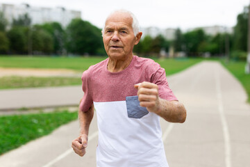 Elderly man with grey hair running in the park