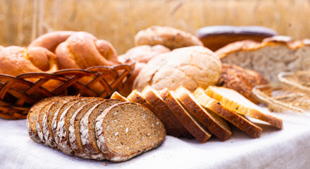 Lot of different flavored bread, wheat, rye, on the table in the field outside