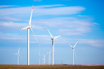 Fleet of power generators in motion. The blades of the wind farm rotate against the sky. The concept of extracting electricity from renewable sources. Wind turbine to generate electricity.