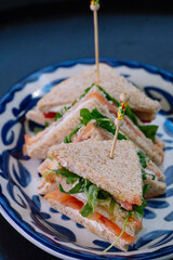 Three delicious smoked salmon sandwiches are artfully arranged on a plate.