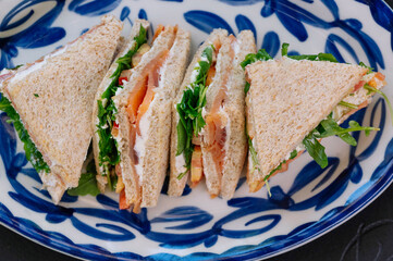 Three delicious smoked salmon sandwiches are artfully arranged on a plate.