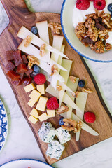 A beautiful overhead shot of a wooden cheese board featuring an assortment of cheeses.