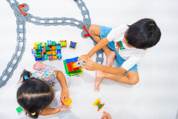 Adorable little child boy and girl enjoying play colorful plastic toy block building