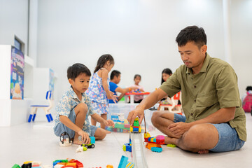 Father play colorful toy block building with adorable kindergarten child boy and girl