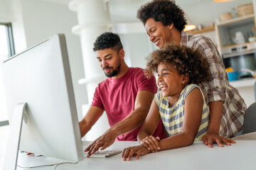 Happy african american family having fun together while using computer together at home