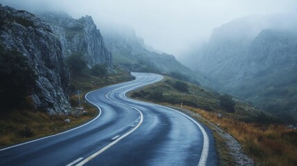 Naklejka premium Winding Asphalt Road Through Misty Mountain Pass