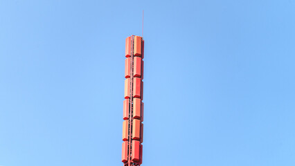 A tall red tower with a red top. The tower is surrounded by a blue sky