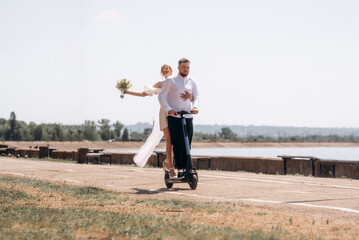 Newlyweds couple riding electric scooter. Rear view. Groom and bride using electric scooter together