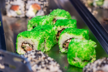 A detailed close up view of several sushi rolls beautifully arranged on a tray