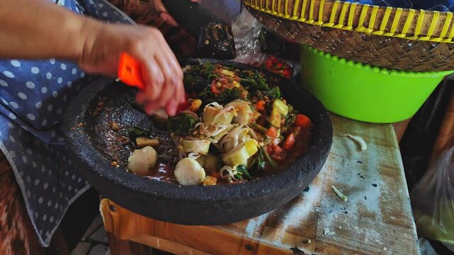 A female chef Preparation for making lotek, a Indonesian food containing rice cake and vegetables drizzled with peanut sauce