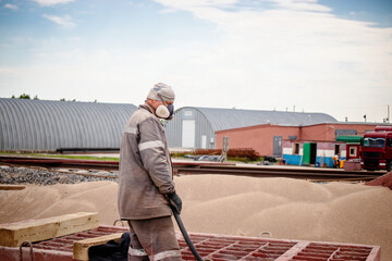 Worker using a sandblaster to remove rust from a metal structure at an industrial plant during...