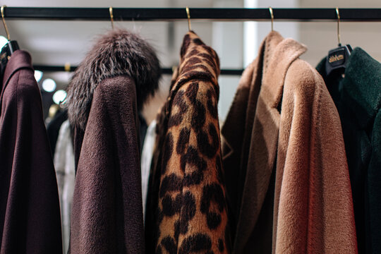 Leopard, brown, purple women fur coats, winter outerwear hanging in a row on hangers in a fashion luxury boutique