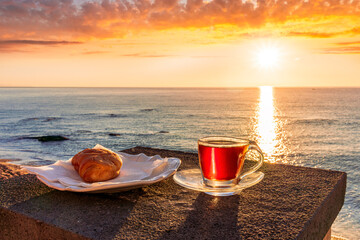 concept of street outdoor breakfast with a cup of tea or coffee on a morning coast during sunrise. landscape of city embarkment with sea water and cloudy sky on background