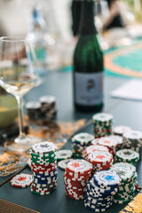 Stacks of casino chips with wine bottle and glass, tabletop gaming and wine tasting concept, at-home entertainment trend