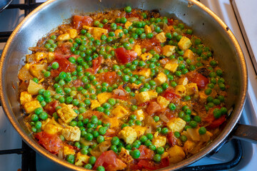 Spicy matar paneer or cottage cheese vegetarian curry cooked with tomatoes Indian style in a frying pan.