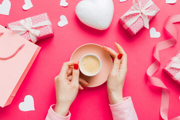 Flat lay of heart shaped cup of black coffee in the hands of women on colored background with copy space top view. Valentine day and holiday concept