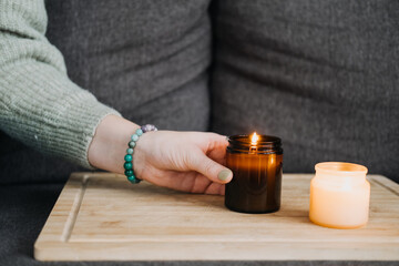 Woman lighting a candle on a wooden surface, creating a warm and cozy atmosphere. Simple moments of relaxation and tranquility at home.
