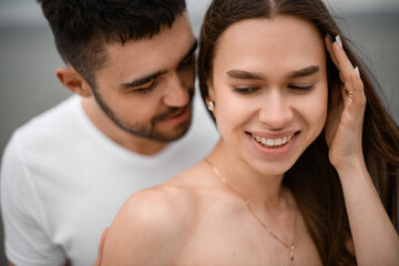 Young pretty woman's face holding her hair out of her face with her hand while a man whispers something gently in her ear