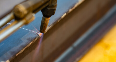 Metal being cut with a torch. Gas cutting metal. Precision and control in metal fabrication process. Sparks fly as flame. Clean, sharp cut. Metalwork and welding. Industrial metal cutting process.
